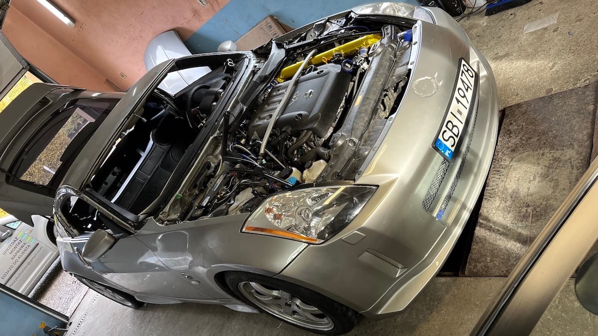 Naprawa szyb w Nissanie 350Z. Samochód stoi w warsztacie bez maski oraz szyb.